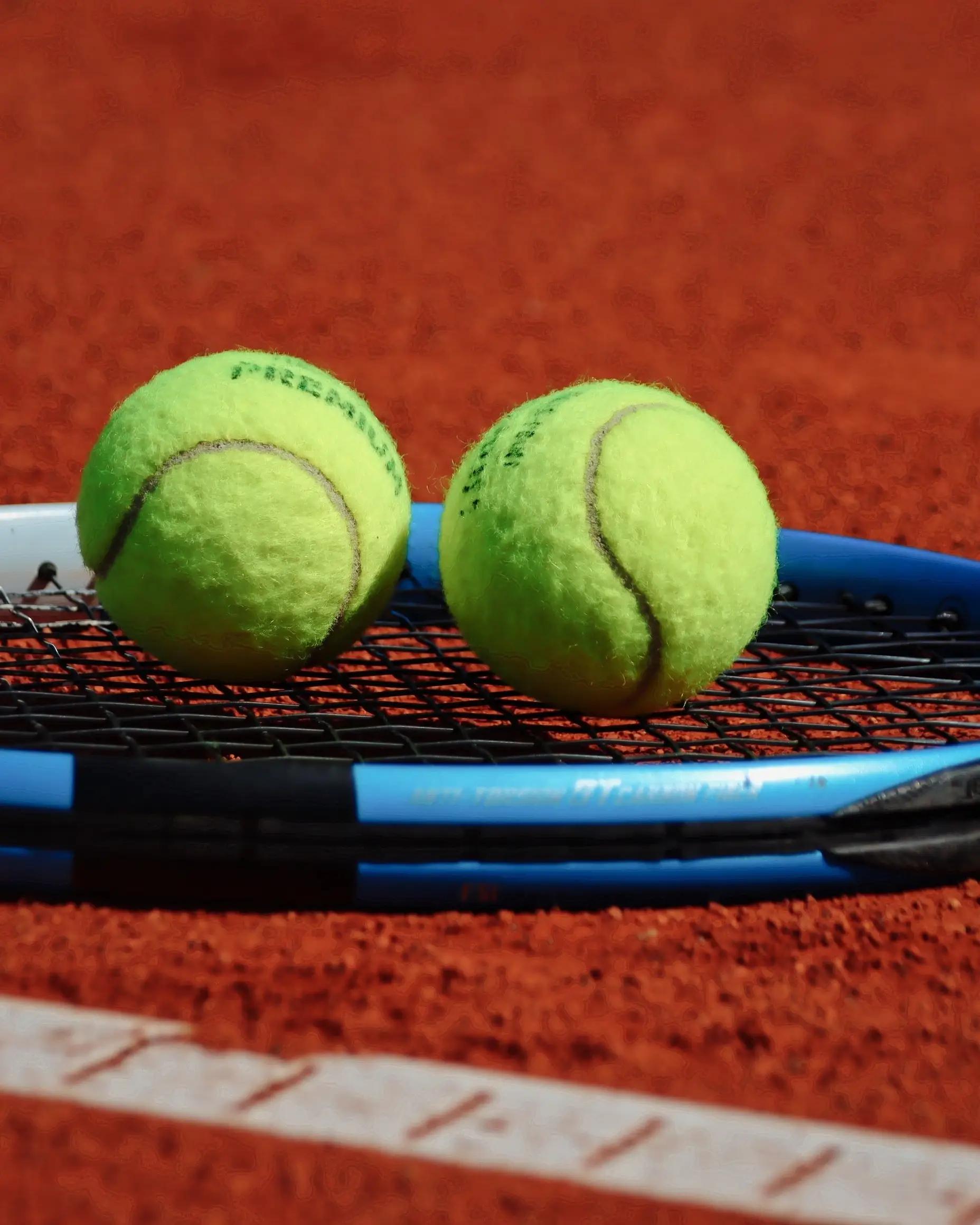Tennis balls on a racket on a grass-style court, representing The Boodles tennis event.
